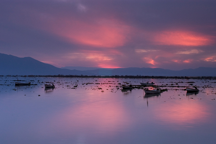 Fotografía de amanecer del lago de Chapala donde se aprecian lanchas de pescadores.